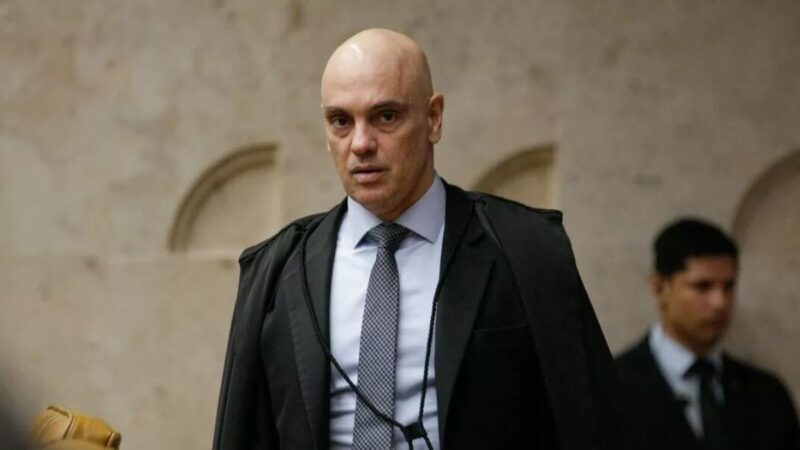 Alexandre de Moraes durante sessão no stf com bandeiras do Brasil e dos EUA ao fundo
