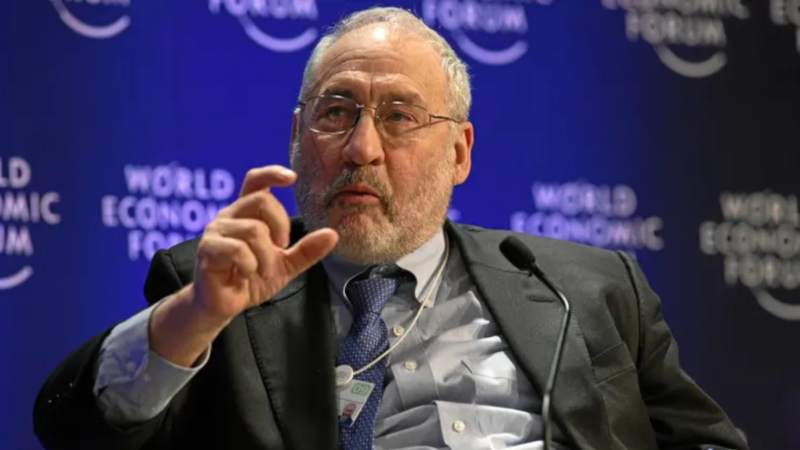 Fotografia dividida mostrando o economista Joseph Stiglitz e um celular com o logotipo do Pix, com as bandeiras do Brasil e dos EUA ao fundo.