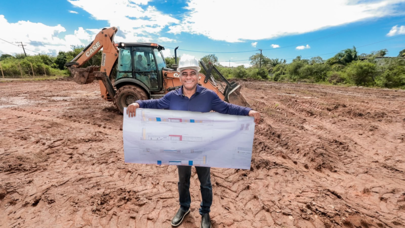Registro do prefeito Del no início da obra, com o terreno e a equipe responsável pela construção ao fundo.