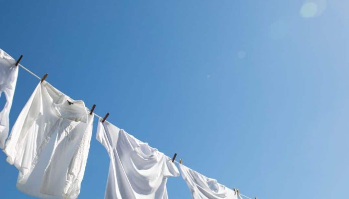 Roupas brancas penduradas em um varal, mostrando peças limpas e impecáveis após remoção de manchas difíceis