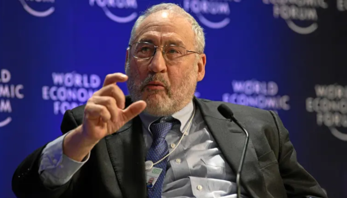 Fotografia dividida mostrando o economista Joseph Stiglitz e um celular com o logotipo do Pix, com as bandeiras do Brasil e dos EUA ao fundo.